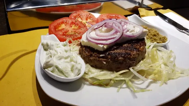 קציצת בשר צלויה עם גבינה וטבעות בצל, פרוסות עגבנייה וכרוב חתוך בצלחת