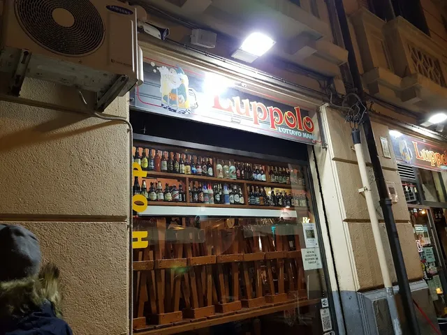 חלון ראווה מלא בקבוקי בירה מתחת לשלט מואר בלילה