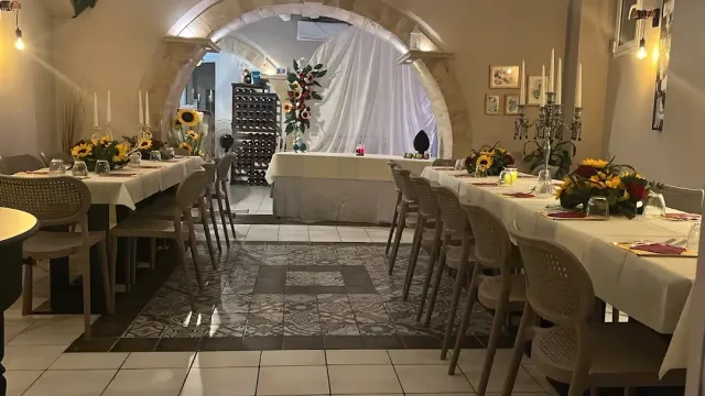 חלל מקומר עם שולחנות ארוכים, זרי חמניות ופמוטים על מפות לבנות