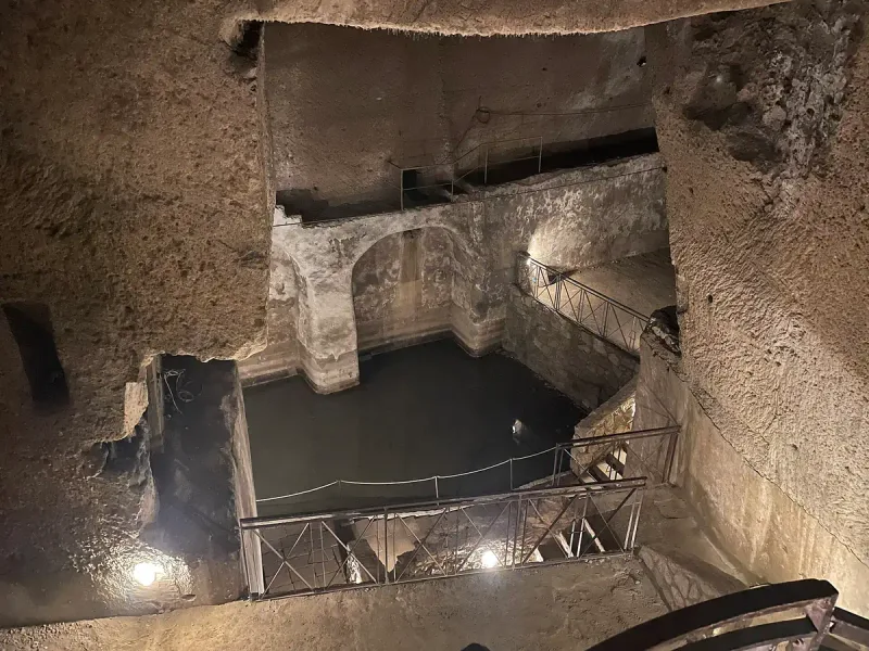 חלל תת קרקעי גדול חצוב באבן בהירה ומוארת נקודתית מתחת לנאפולי