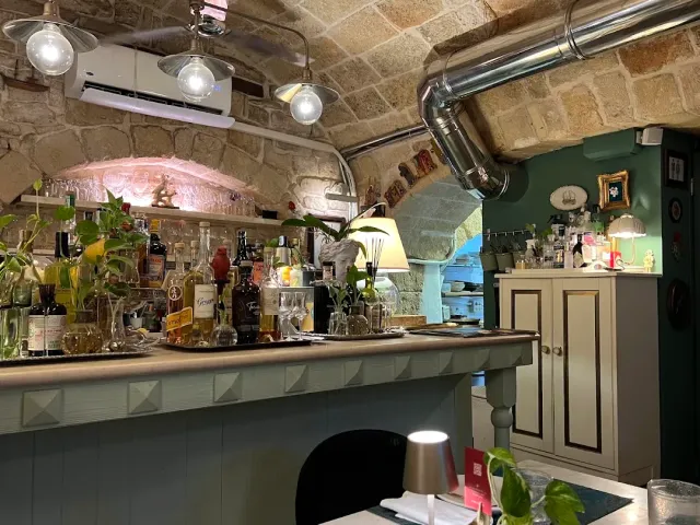 חלל אבן מקומר עם דלפק ירוק, בקבוקים, צמחים וצינור מתכת מבריק