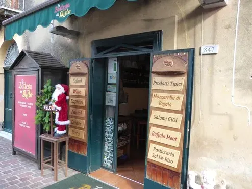 כניסת חנות עם סוכך ירוק, שני לוחות תפריט צדדיים ובובת סנטה קלאוס אדומה