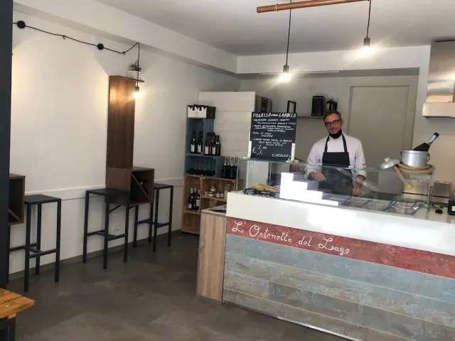דלפק תצוגה בחלל לבן, עובד בסינר עומד מאחוריו וכיסאות בר גבוהים בצד