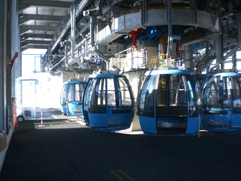 קבינות רכבל כחולות זו אחר זו בתוך תחנת הרכבל באלפה די סיוזי