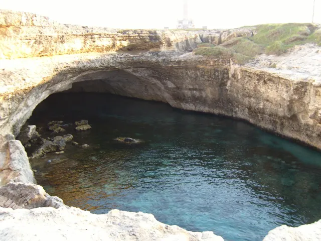 בריכת ים עגולה בתוך סלע עם מים טורקיז ופתח לים